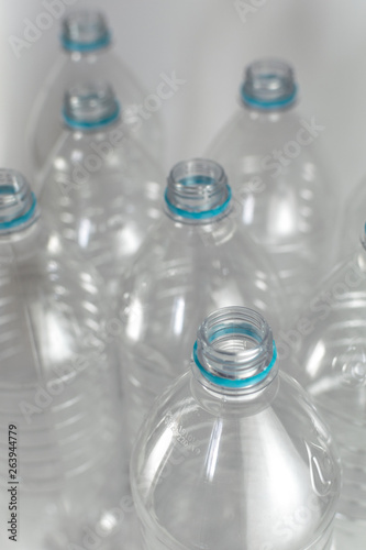 Bottlenecks of a pack of liter and a half of empty mineral water without caps just with the blue sealing ring on a white background. Reuse, Eco-Friendly, Environment, Conservation, Sustainable