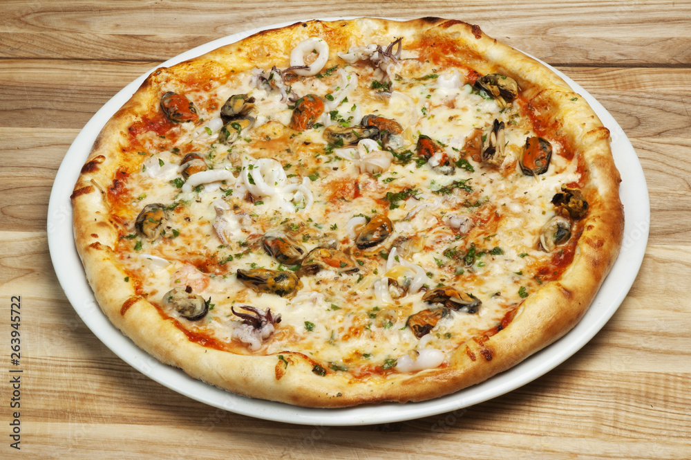 Delicious pizza with cheese, mushrooms and seafood on a wood background