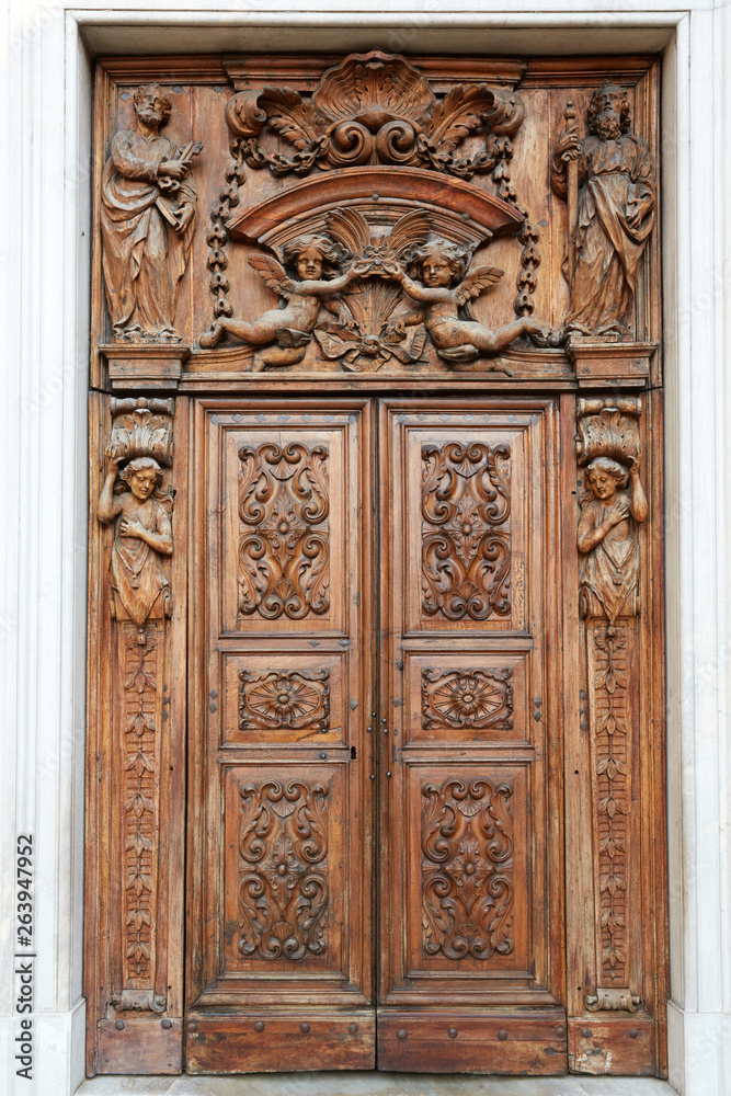 Ancient wooden church portal with sculpures and decorations in Piedmont, Italy