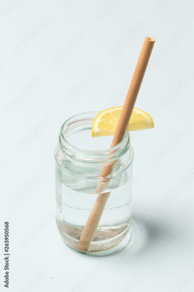 Bamboo straw in a glass of lemon water on the blue background, Reusable bamboo straws as an alternative for single-use plastic straws, healthy and sustainable lifestyle concept Bamboo straw in a glass of lemon water on the blue background, Reusable bamboo straws as an alternative for single-use plastic straws, healthy and sustainable lifestyle concept