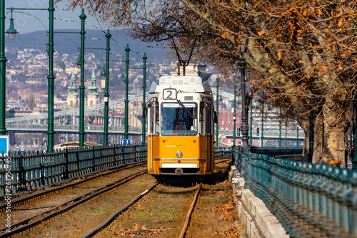 Hungary, Budapest: Street view with famous historic orange tram cable car in the city center of the Hungarian capital with cityscaepe and blue sky in the background - travel history.
