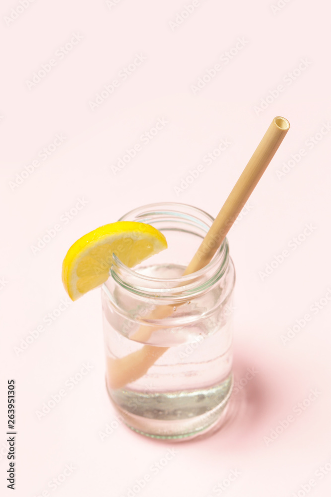 Bamboo straw in a glass of lemon water on the pink background, Reusable bamboo straws as an alternative for single-use plastic straws, healthy and sustainable lifestyle concept Bamboo straw in a glass of lemon water on the pink background, Reusable bamboo straws as an alternative for single-use plastic straws, healthy and sustainable lifestyle concept
