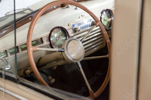 View from opened window with the steering wheel and the interior of the old Russian car of the executive class released in the Soviet Union beige GAZ m-20 pobeda
