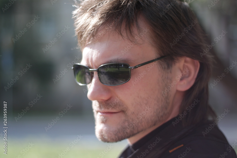 a man in a black jacket and sunglasses in the park a man in a black jacket and sunglasses in the park