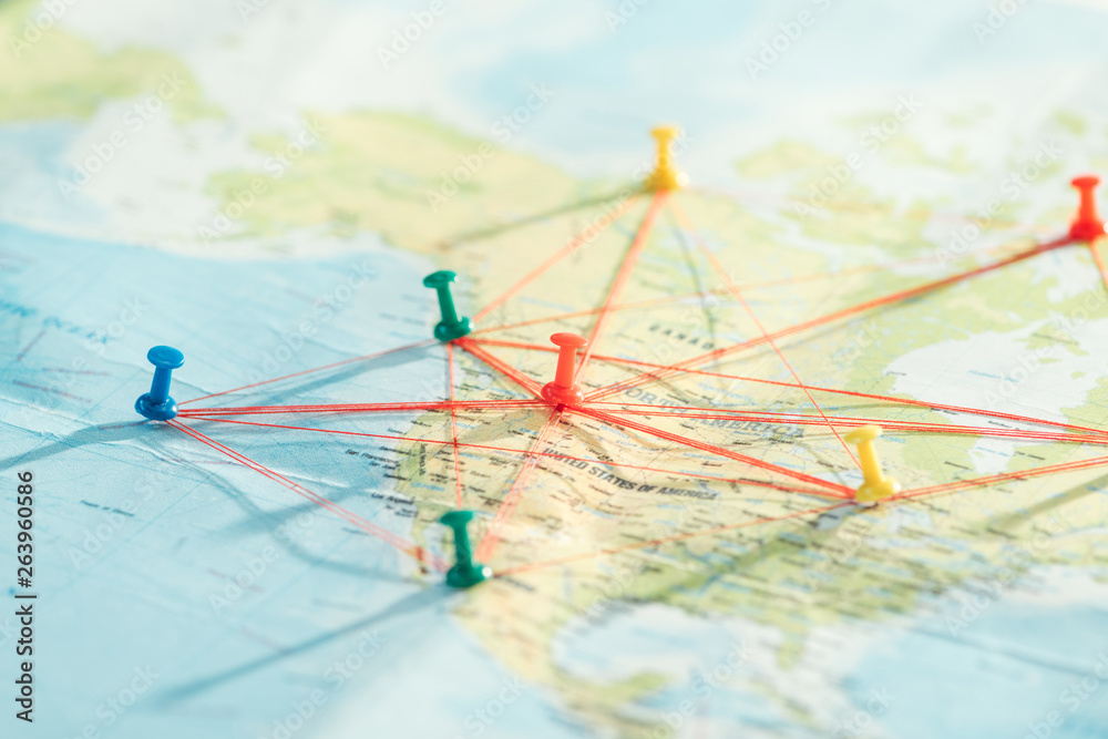Selective focus of push pins and strings on world map - obrazy, fototapety, plakaty 