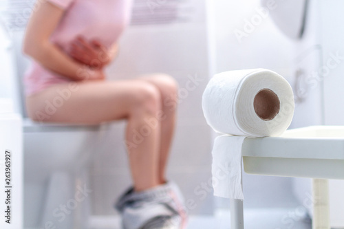 Ill, unwell woman suffering from diarrhea, constipation and cystitis at toilet. Stomach pain during PMS. Health care and pain concept photo