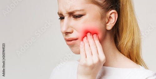 Frustrated young woman with toothache touching her cheek photo