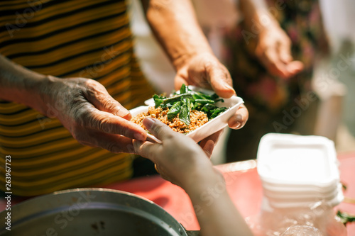 Volunteers provide food for beggars : Concepts Feeding and help : The hands of the rich give food to the hands of the poor