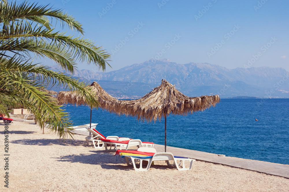 Summer beach vacation.  Sunny Mediterranean landscape with beach umbrellas. Montenegro, Adriatic Sea,  Bay of Kotor, Herceg Novi
