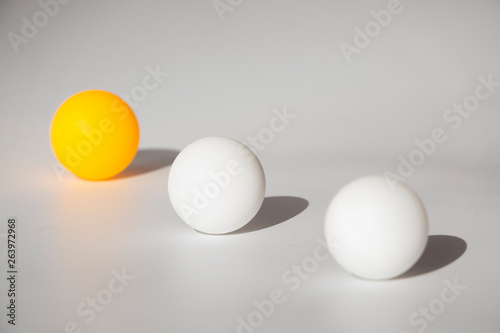 Yellow and white ping pong balls on a white background with hard light and shadows