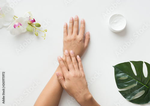 Woman putting cream on her hands on white background