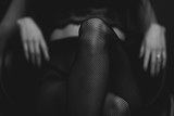slim sexy woman in black stockings sits on a chair on a black background. black and white