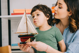 Mother and surprised kid with toy ship in living room