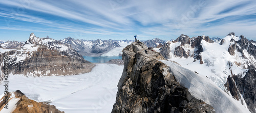 Greenland, Sermersooq, Kulusuk, Schweizerland Alps, mountaineer with raised arms on summit photo