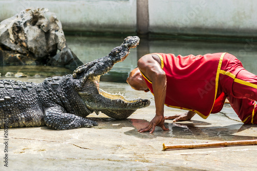 A man is showing his head into the open mouth of the crocodile.