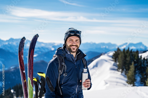 Germany, Bavaria, Brauneck, portrait of smiling man on a ski tour in winter in the mountains having a break