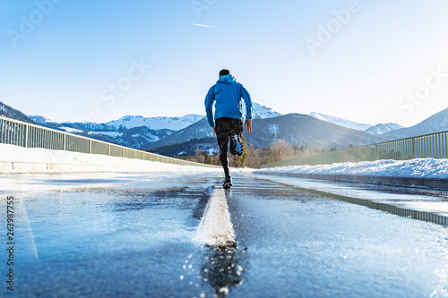 Germany, Bavaria, sportive man running on a road in winter photo