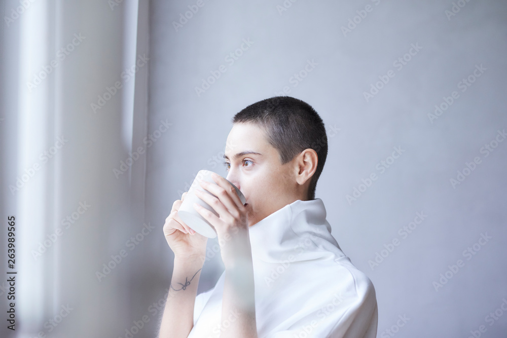 Portrait of short-haired young woman drinking from mug Portrait of short-haired young woman drinking from mug