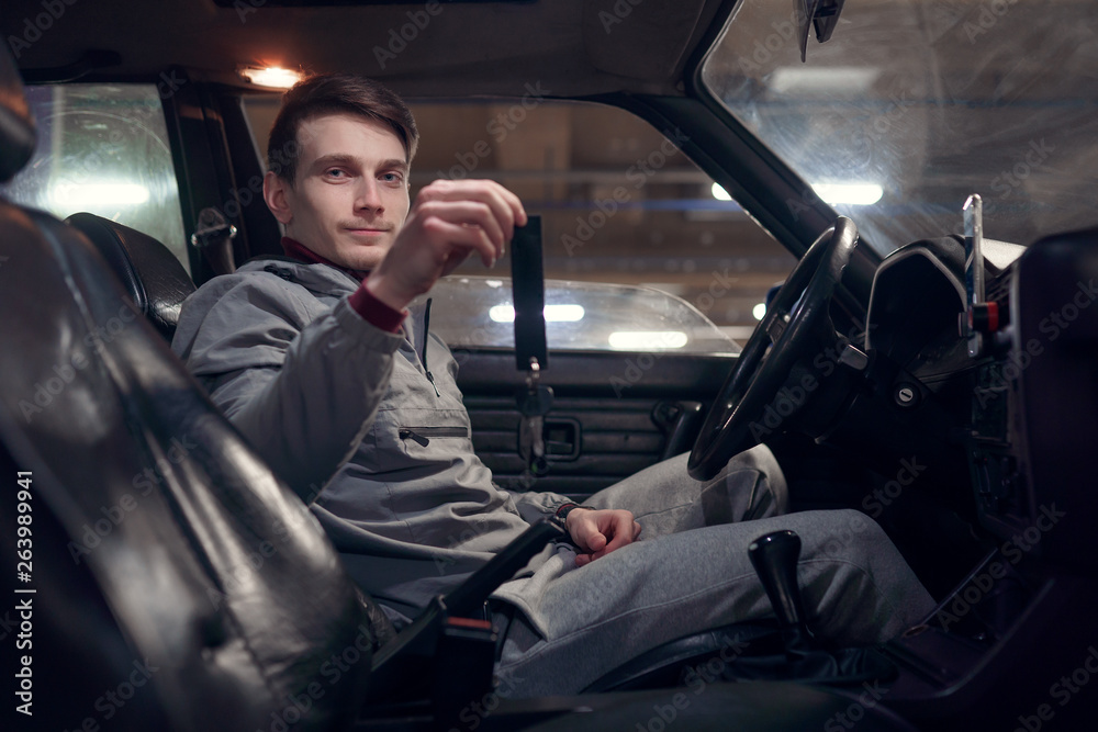 Photo of side of man driver holding keys sitting in car . Photo of side of man driver holding keys sitting in car .