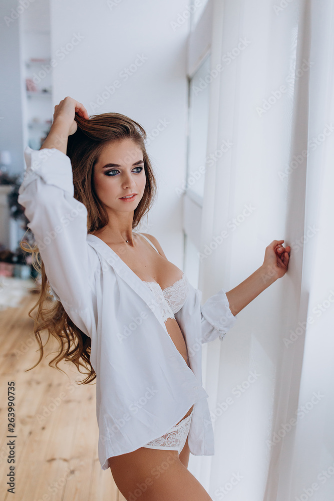Photo shoot a young girl in white lingerie at the window. Photo shoot a young girl in white lingerie at the window.