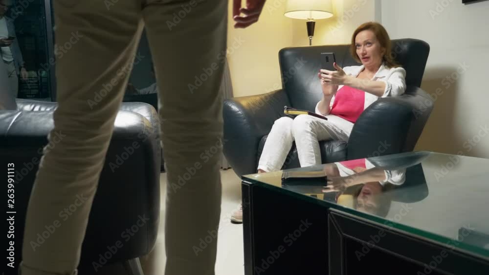 concept of negotiation. A woman with a telephone in her hands communicates with a man. In the evening I sit in the office in a leather chair. typing a message on a smartphone while talking concept of negotiation. A woman with a telephone in her hands communicates with a man. In the evening I sit in the office in a leather chair. typing a message on a smartphone while talking