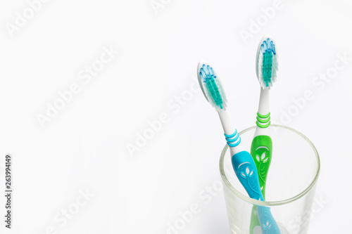 Set of toothbrushes in glass on white background.