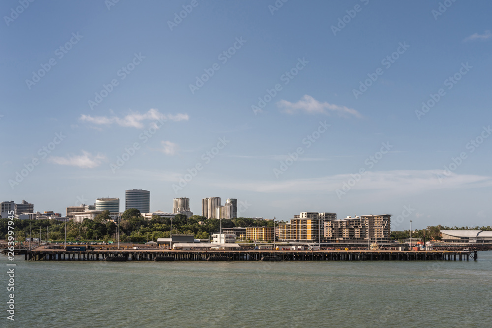 Darwin Australia - February 22, 2019: Darwin skyline seen from south upon harbour bay water under blue sky. Convention center to the right. Dock for larger ships up front. 