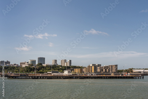 Darwin Australia - February 22, 2019: Darwin skyline seen from south upon harbour bay water under blue sky. Convention center to the right. Dock for larger ships up front. 