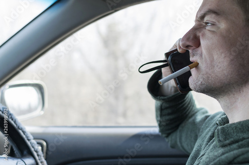 A young man rides in a car and talks on the phone with anger.