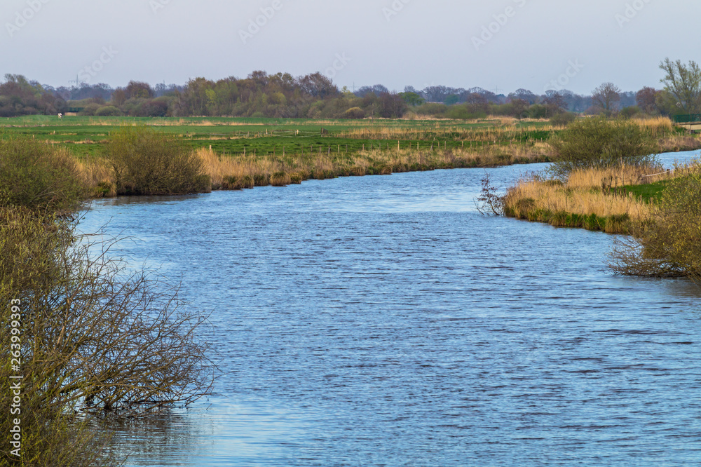 A shallow river winds its way through the east frisian landscape. A nature reserve in Germany near Timmel.