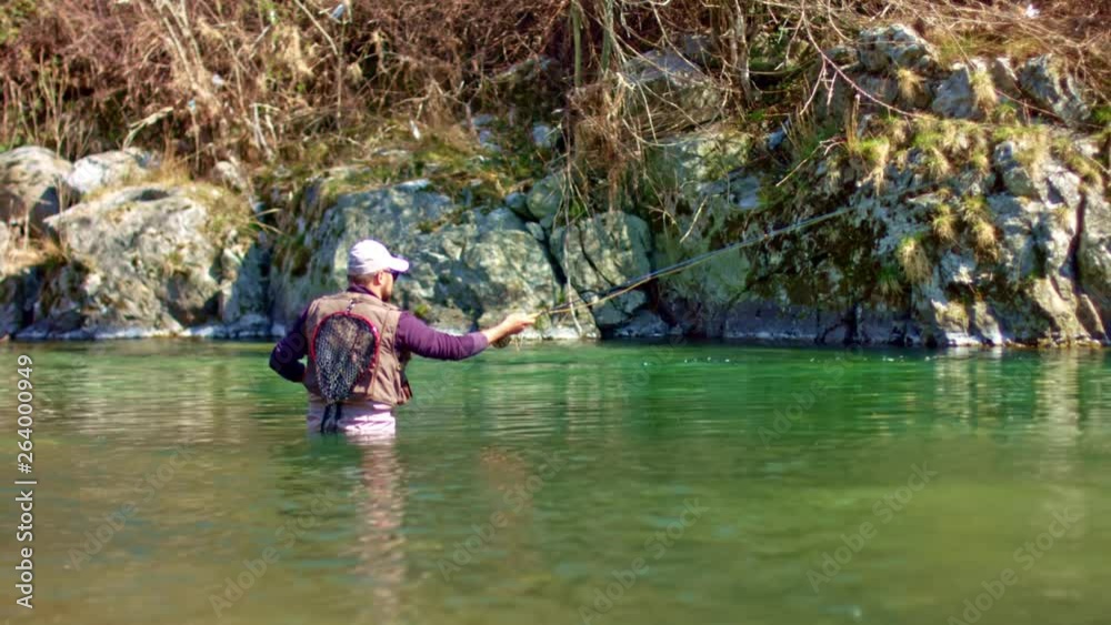 Flyfish fisherman in river looking for fishes Flyfish fisherman in river looking for fishes