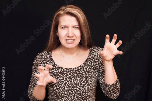 Canvas Print Woman wearing a leopard costume on a dark background roar and waving her arms li