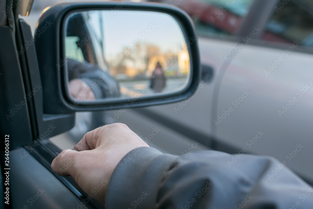 a man's hand on the car door on the background of a female silhouette in the mirror of the rear view mirror