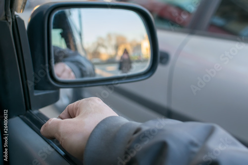 a man's hand on the car door on the background of a female silhouette in the mirror of the rear view mirror © Евгений Медведев