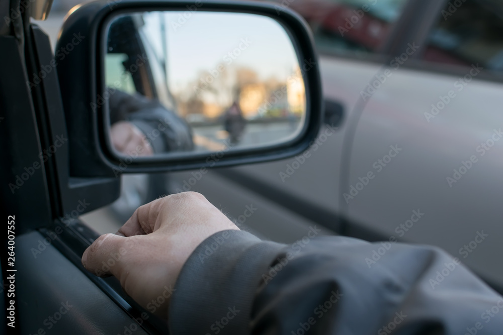 a man's hand on the car door on the background of a female silhouette in the mirror of the rear view mirror