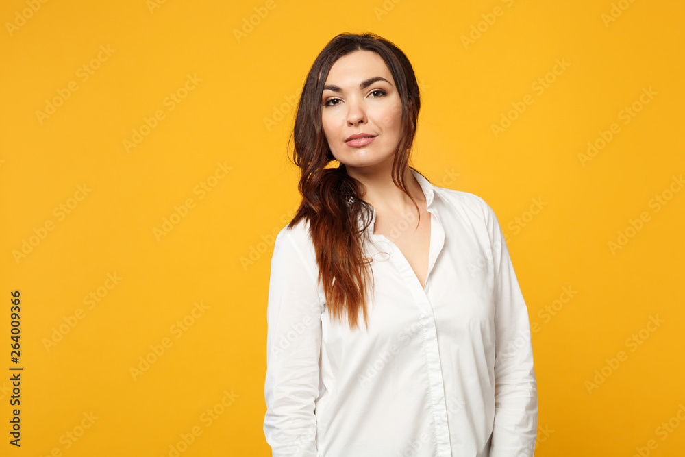 Portrait of attractive young woman in white shirt, jeans standing and looking camera isolated on yellow orange wall background in studio. People sincere emotions lifestyle concept. Mock up copy space. Portrait of attractive young woman in white shirt, jeans standing and looking camera isolated on yellow orange wall background in studio. People sincere emotions lifestyle concept. Mock up copy space.