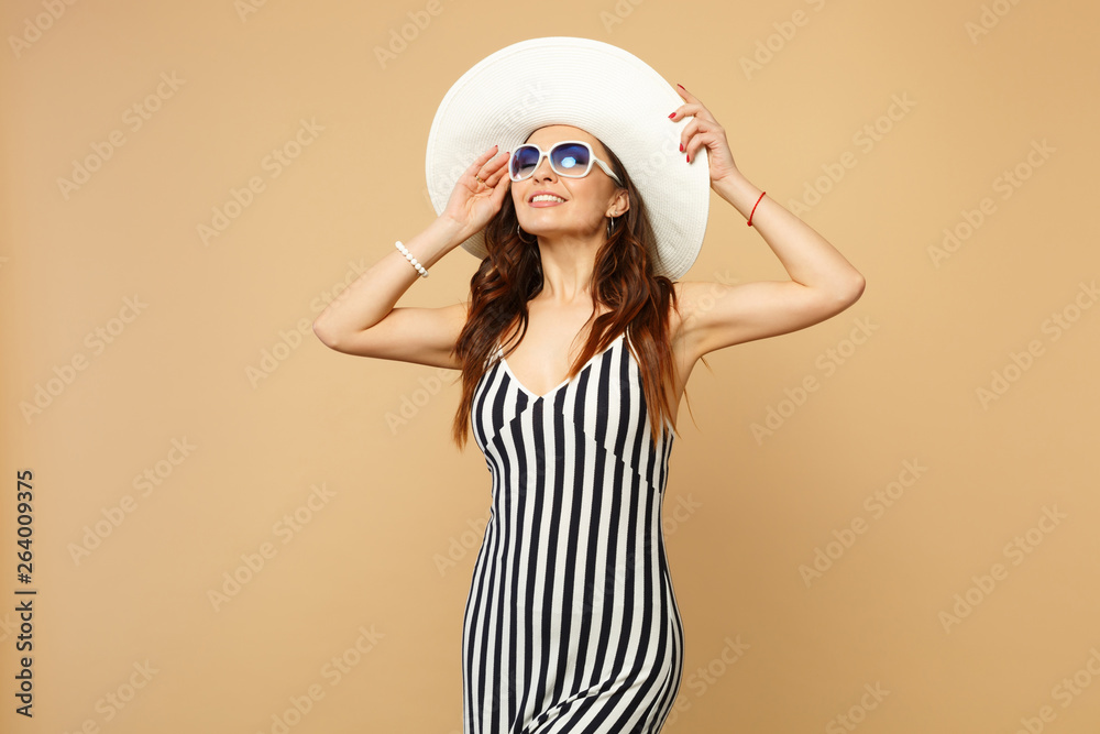 Tender young woman in black and white striped dress, hat and sunglasses keeping eyes closed isolated on pastel beige wall background. People sincere emotions, lifestyle concept. Mock up copy space. Tender young woman in black and white striped dress, hat and sunglasses keeping eyes closed isolated on pastel beige wall background. People sincere emotions, lifestyle concept. Mock up copy space.