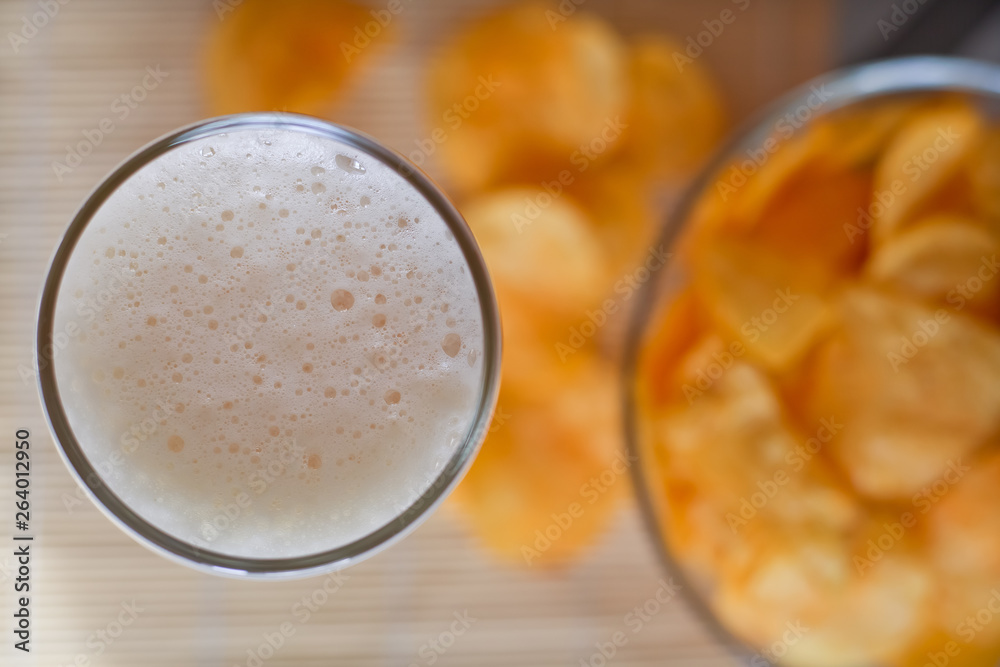 a bowl of potato chips out of focus and a glass of wheat beer top view a bowl of potato chips out of focus and a glass of wheat beer top view