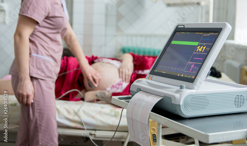 Pregnant woman with electrocardiograph check up for her baby. Fetal heart monitoring. Diagnostic, healthcare, medical service