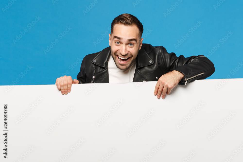 Handsome young unshaven man hold big white empty blank billboard for promotional content isolated on blue wall background studio portrait. People sincere emotions lifestyle concept. Mock up copy space Handsome young unshaven man hold big white empty blank billboard for promotional content isolated on blue wall background studio portrait. People sincere emotions lifestyle concept. Mock up copy space