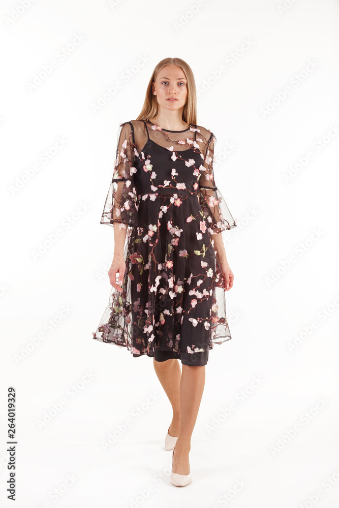 Beautiful young blonde woman in black dress with floral embroidery isolated on white background Beautiful young blonde woman in black dress with floral embroidery isolated on white background