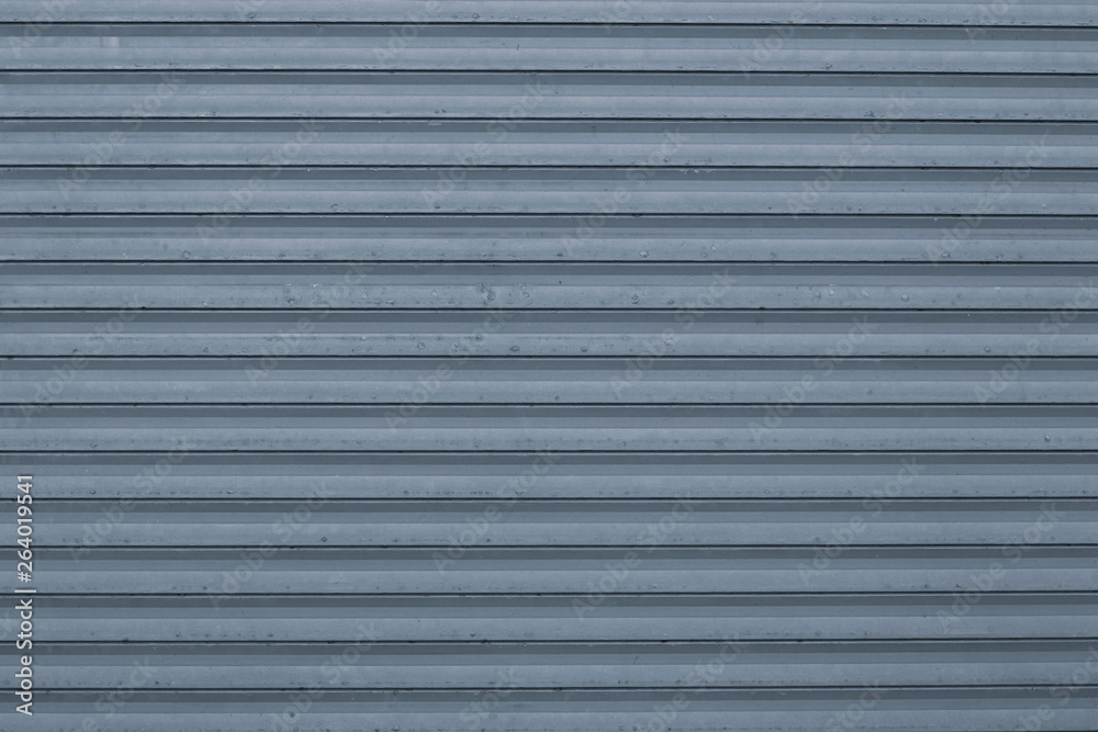 Texture of blue and gray corrugated metallic surface. Blue ribbed background with stripes, straight lines. Modern pattern of blue metal jalousie.