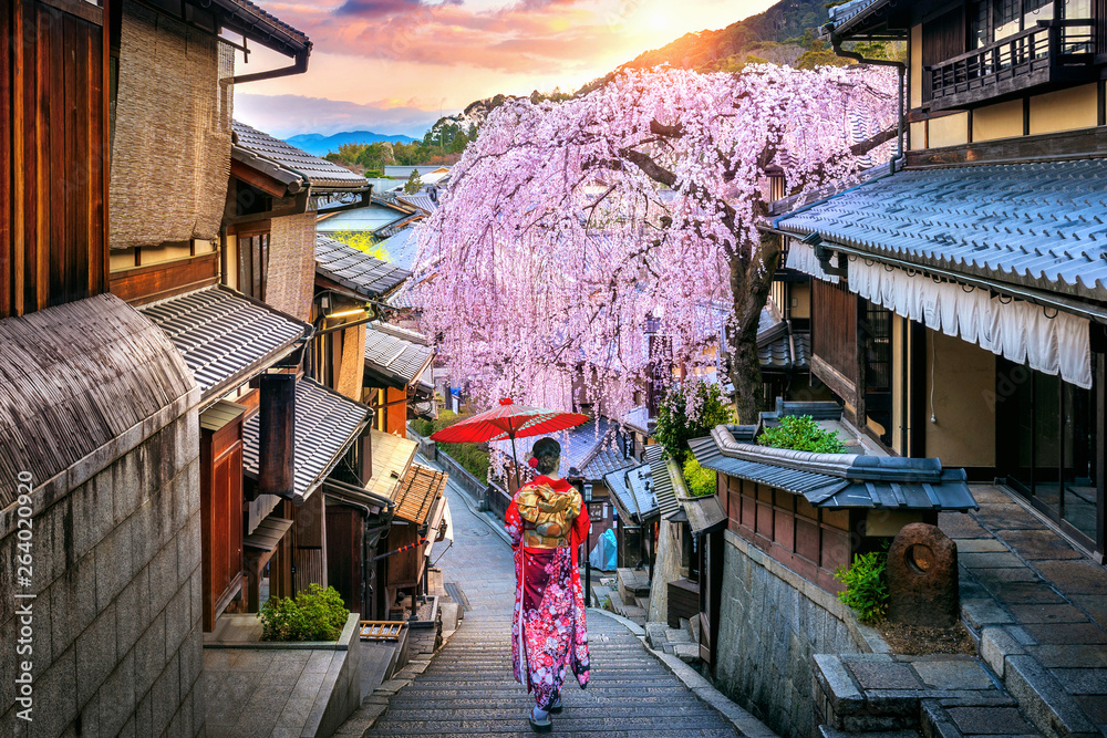 Naklejka premium Kobieta ubrana w tradycyjne japońskie kimono spaceru w historycznej dzielnicy Higashiyama wiosną, Kioto w Japonii.