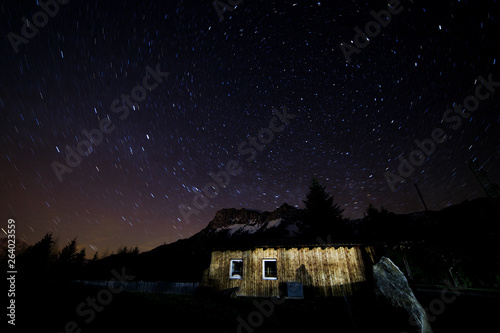 long time exposure with polaris and colorful star trails in the austrian alps with a cabin photo