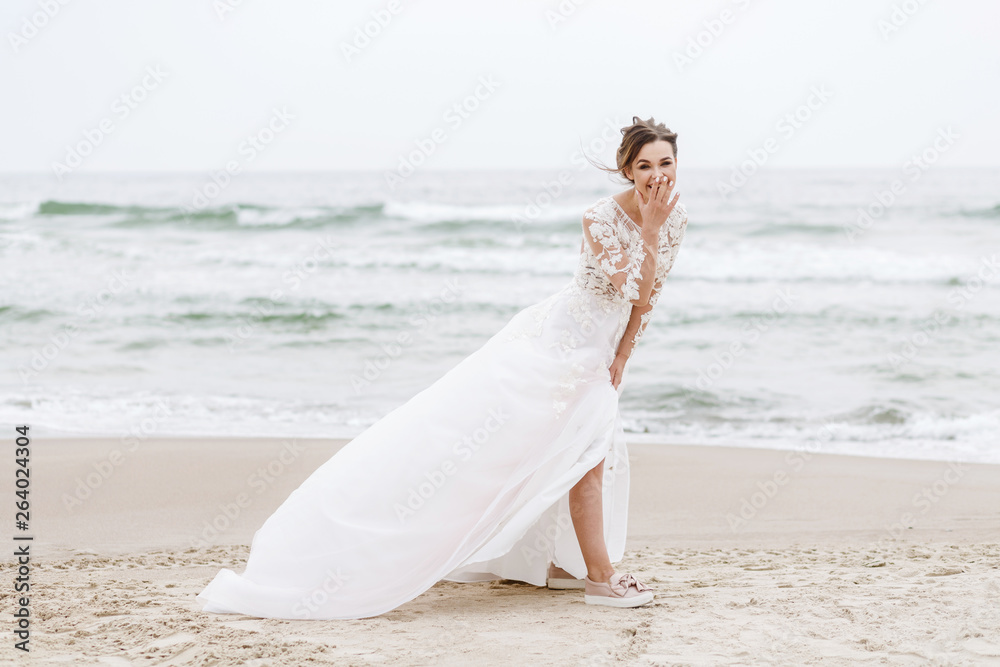 positive bride runs on the sea beach on an overcast day positive bride runs on the sea beach on an overcast day
