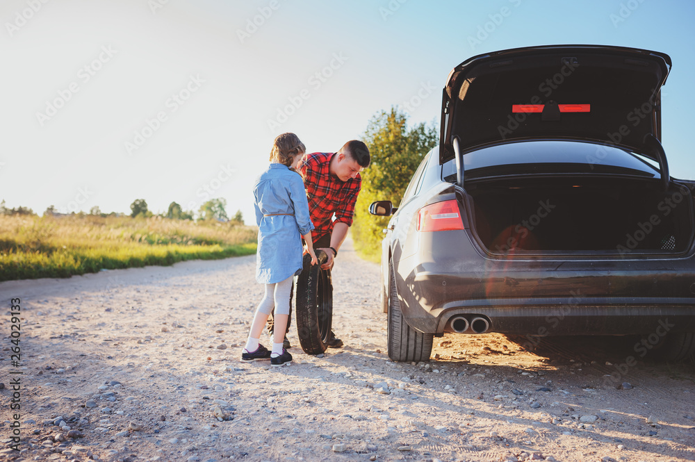 father and daughter changing broken tire during summer rural road trip. Kid helping to fix problems with car father and daughter changing broken tire during summer rural road trip. Kid helping to fix problems with car