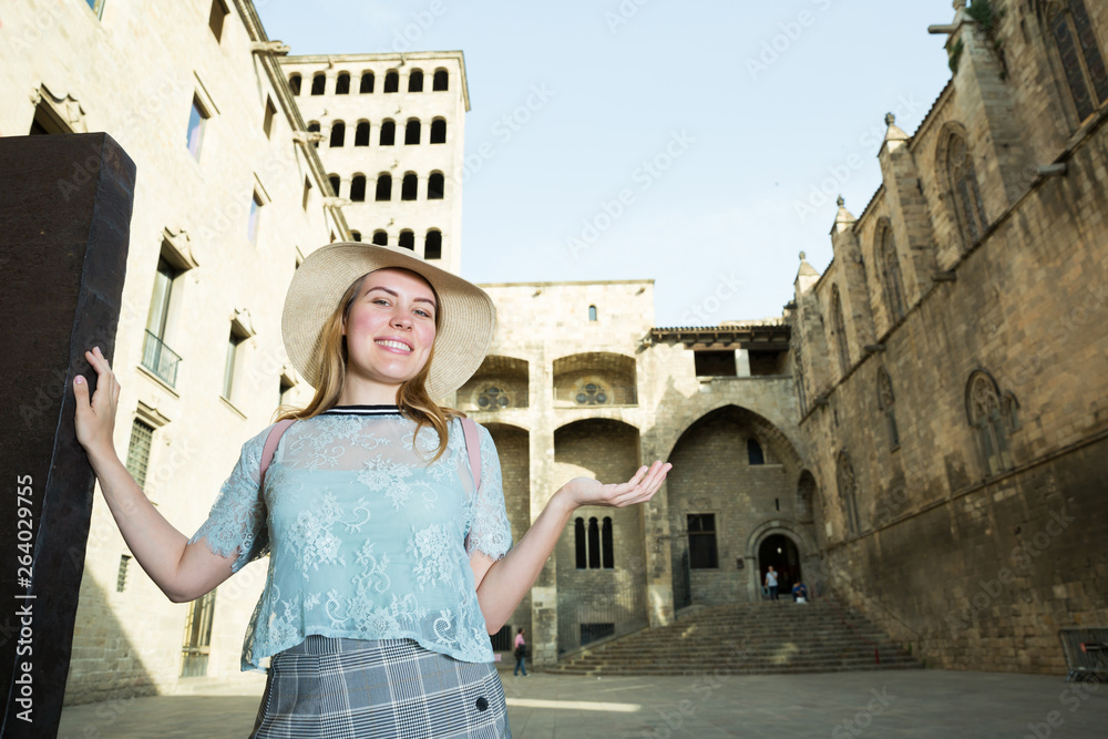 Cheerful young woman standing at the street among architecture