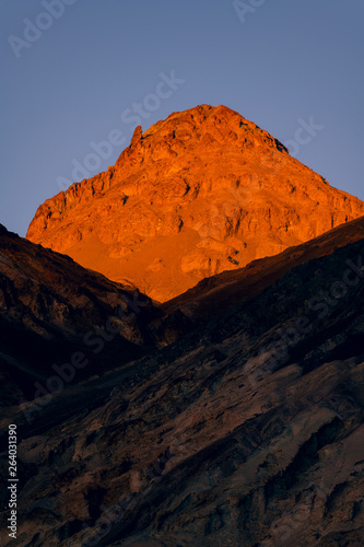 High desert peak bathed n the golden light of sunset above a ridge that is in shadow - Death Valley National Park