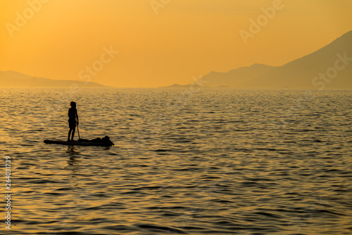 Silhouette of young couple on stand up paddle board. Active vacation, beach life.