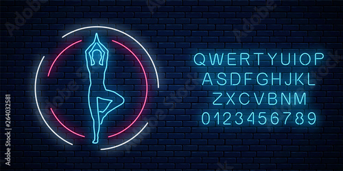 Neon glowing sign of yoga exercices club in circle frame with alphabet. Street lights signboard of gymnastics.